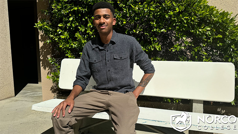 A picture of Brandon sitting on a bench at Norco College.