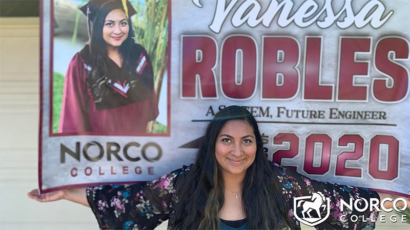 A picture of Vanessa Robles with her graduation banner from Norco College.