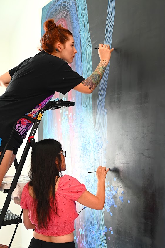 Associate Professor of Art Trang Lê and Natalie Nicole work together on fine-line brushwork for one of the five large-scale paintings during the professional internship.